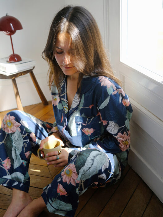 Woman in floral pajamas holding a coffee mug.