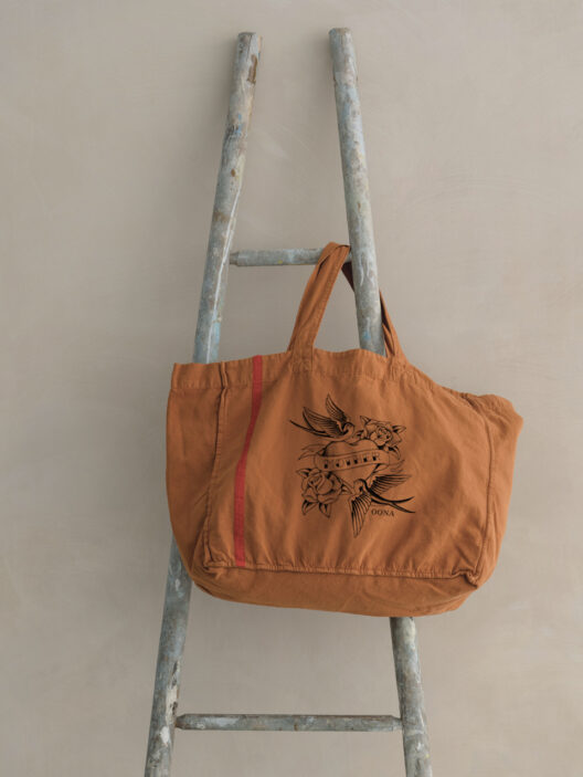 Orange tote bag with tattoo design on ladder