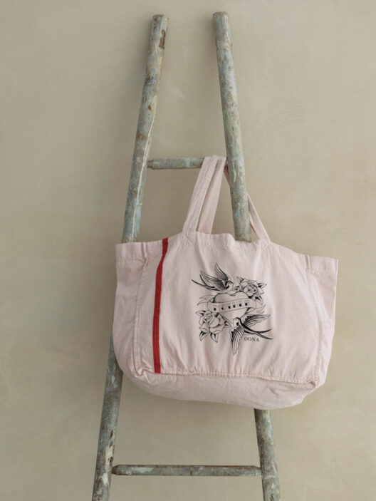 Pink tote bag with floral bird design on ladder.