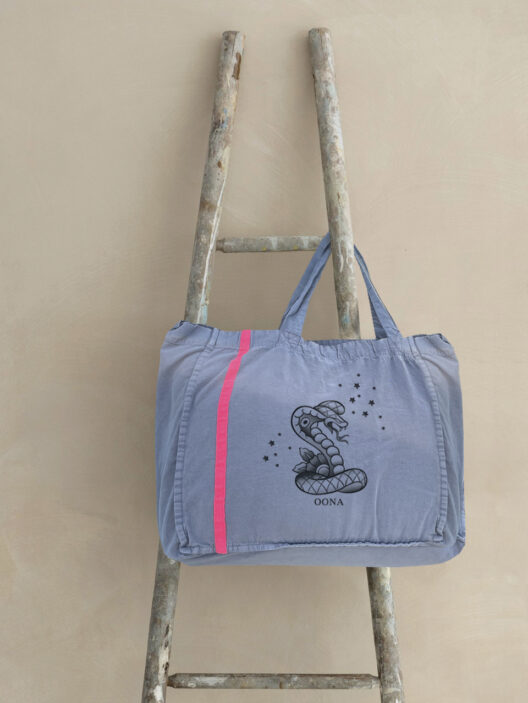 Graue Tasche mit Schlangenmotiv auf Holzleiter