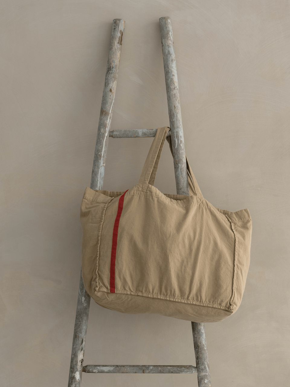 Sac beige sur échelle métallique contre mur.