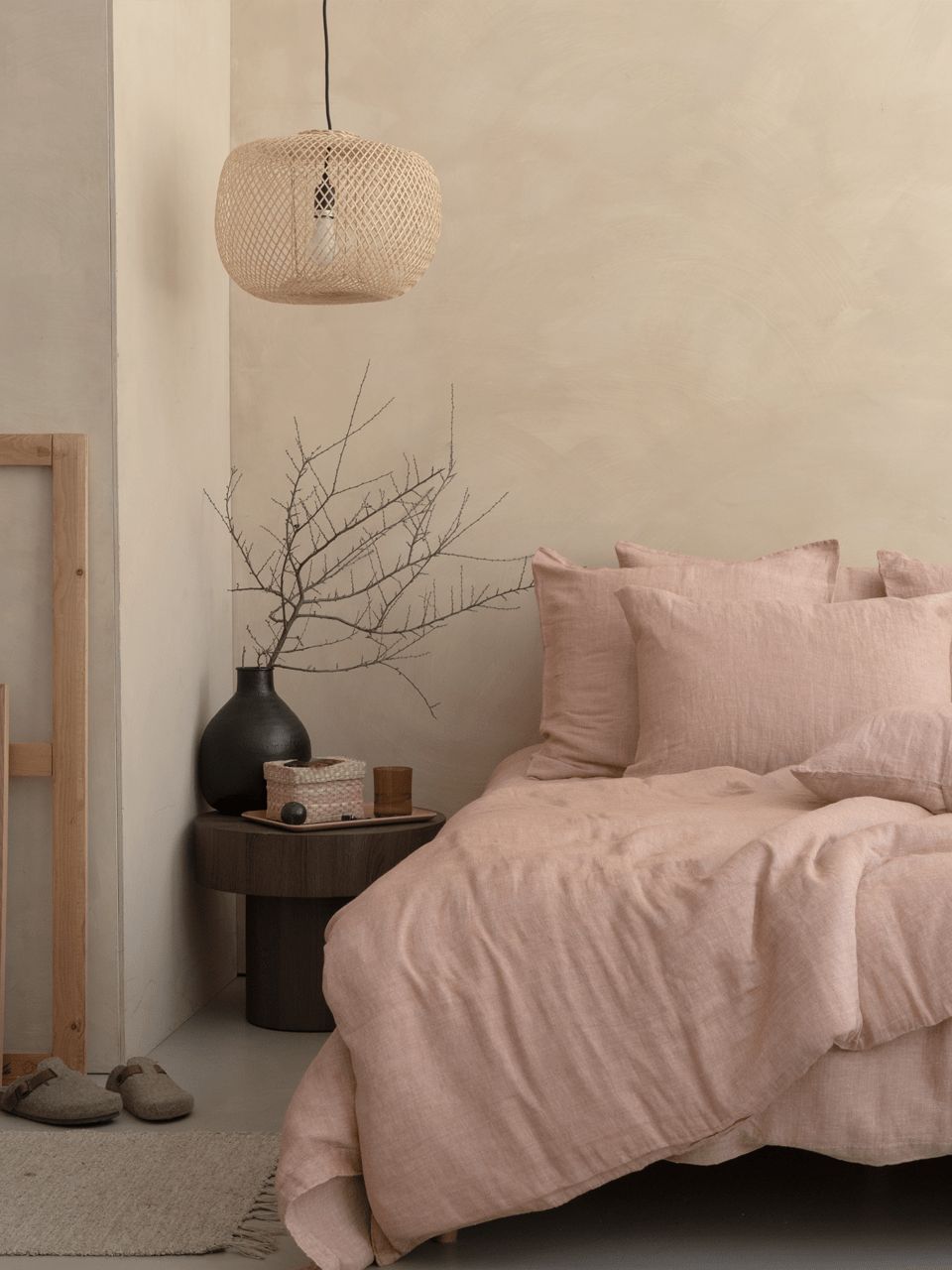 Chambre beige avec lit et lampe suspendue.