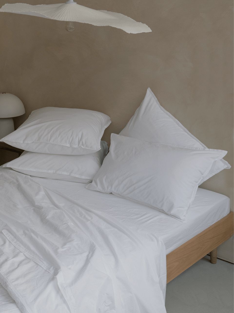 Lit avec oreillers et draps blancs.