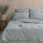 housse couette seafoam 1 1.jpg Lit avec linge bleu dans une chambre apaisante.
