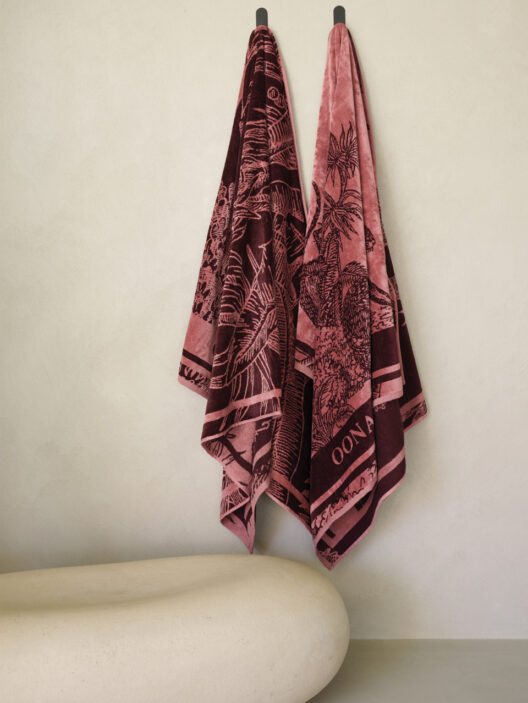 Deux serviettes roses suspendues au mur beige.