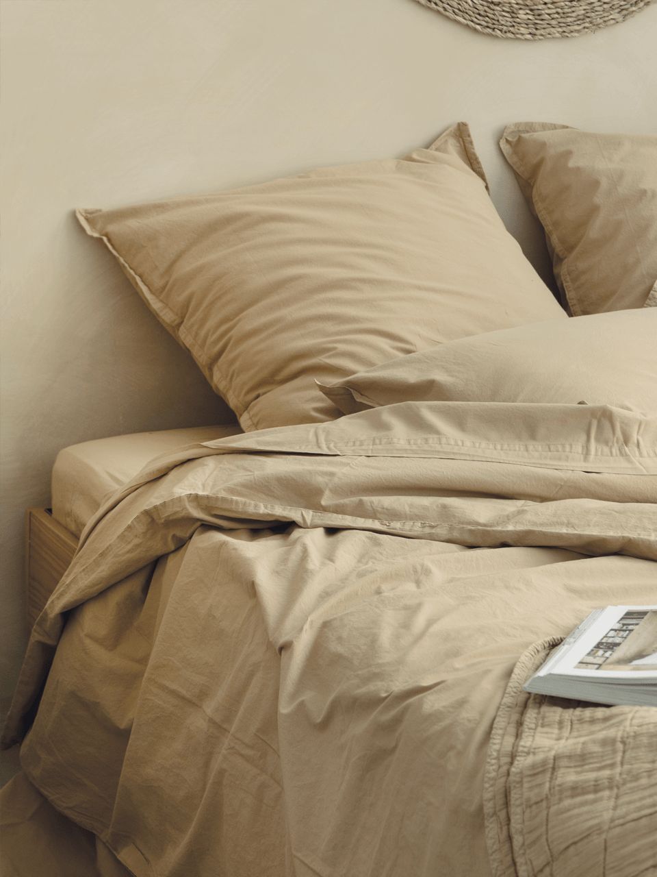 Lit beige avec coussins.