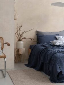 Chambre moderne avec literie bleue et chaise en rotin.