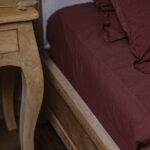 Lit en bois avec draps marron et table de chevet.