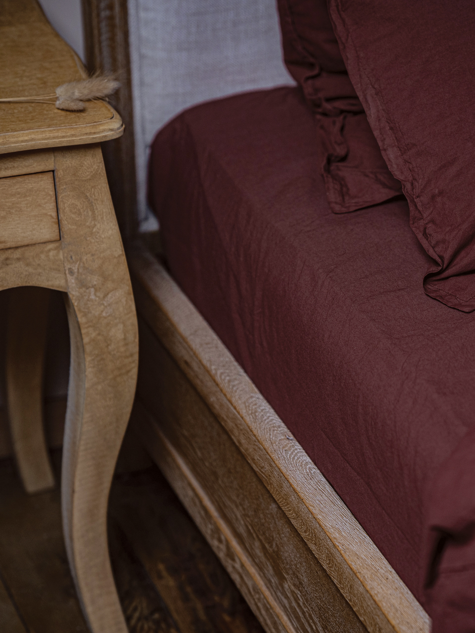 Lit en bois avec draps marron et table de chevet.