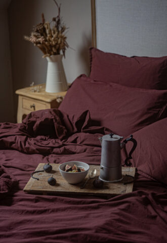 Petit-déjeuner sur lit avec draps bordeaux.