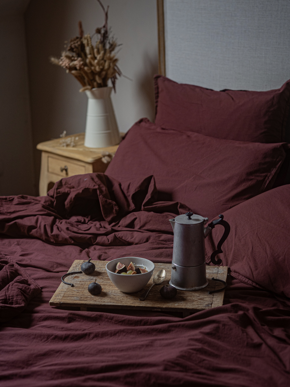Petit-déjeuner sur lit avec draps bordeaux.