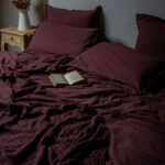 Lit avec couverture bordeaux et livre ouvert.