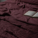 Livre ouvert sur couverture de lit bordeaux.