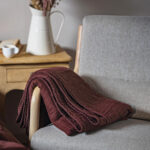 screenshot Couverture prune sur fauteuil gris avec vase.