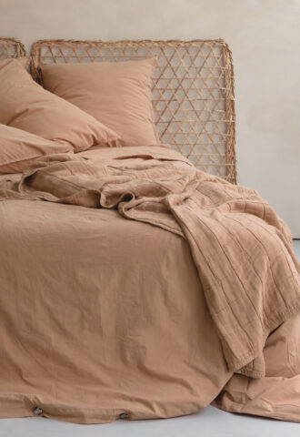 Lit avec draps beige et tête en rotin