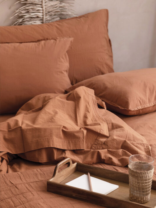 Lit avec linge de lit terracotta et plateau