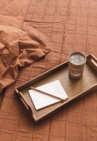 Plateau en bois avec carnet et verre d’eau