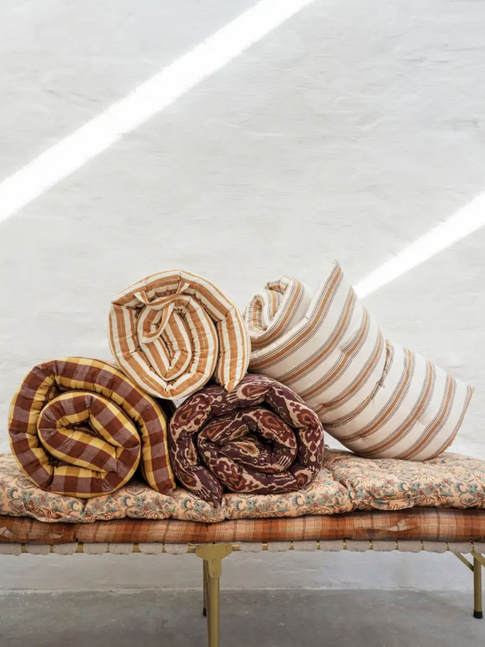 mattress madam stoltz Matelas roulés à motifs posés sur un banc