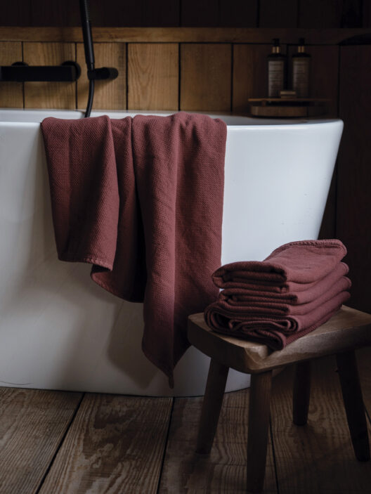 Serviettes bordeaux près d’une baignoire dans salle de bain boisée